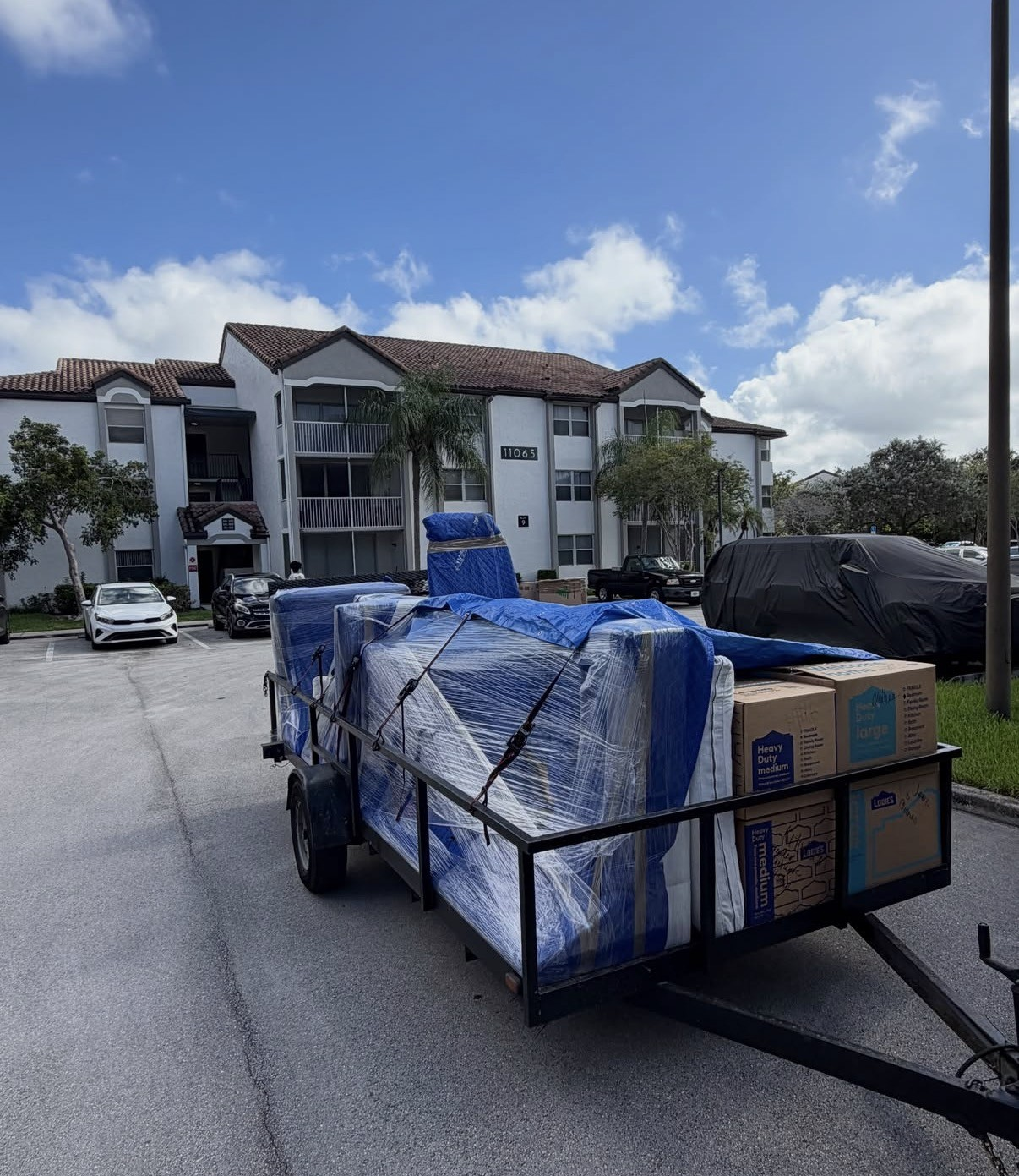 Utility trailer loaded with wrapped furniture and moving boxes for a residential cleanout